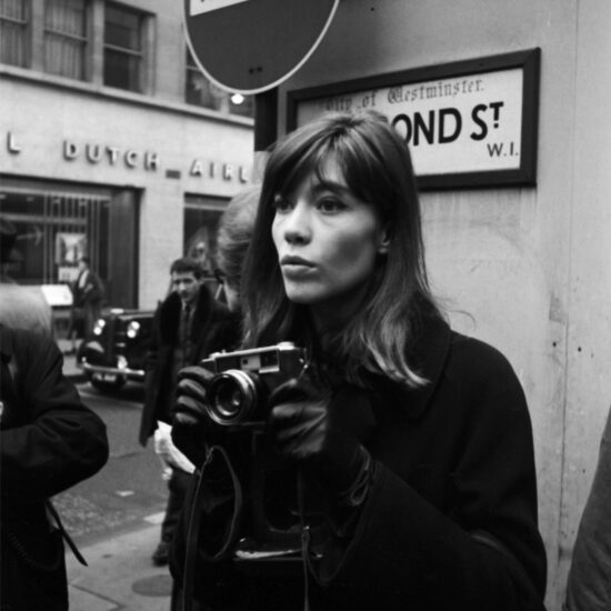 French singer-songwriter Françoise Hardy holds an SLR and stares into the distance under a No Entry sign on New Bond Street in London’s West End, circa early 1964