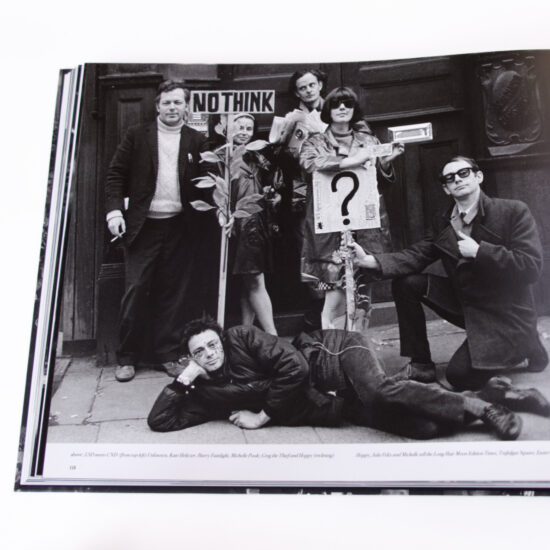 An open copy of the book FROM THE HIP - Photographs by JOHN 'HOPPY' HOPKINS 1960-66 on a white background. The page features a photograph of  L-R: Jeff Nuttall, John 'Hoppy' Hopkins (lying down), Kate Heliczer, Harry Fainlight, Michelle Poole, Greg the Thief, prior to attending the last day of the Aldermaston-London Campaign for Nuclear Disarmament rally in Trafalgar Square on Easter Monday, 11 April 1966.