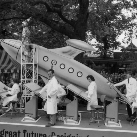 During the 1962 Festival of Labour in Battersea Park, a float takes part in a parade. The float is titled 'Designing a great future - Designing a Great Britain' and has people dressed as scientists and astronauts working at draughting tables, as well as a futuristically-styled rocket ship