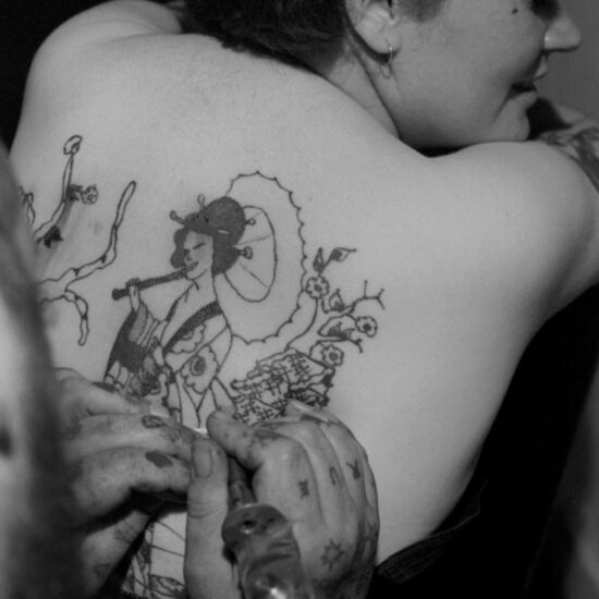 A woman has a large Japanese-style design tattooed onto her back by Tattoo Bill in Notting Hill