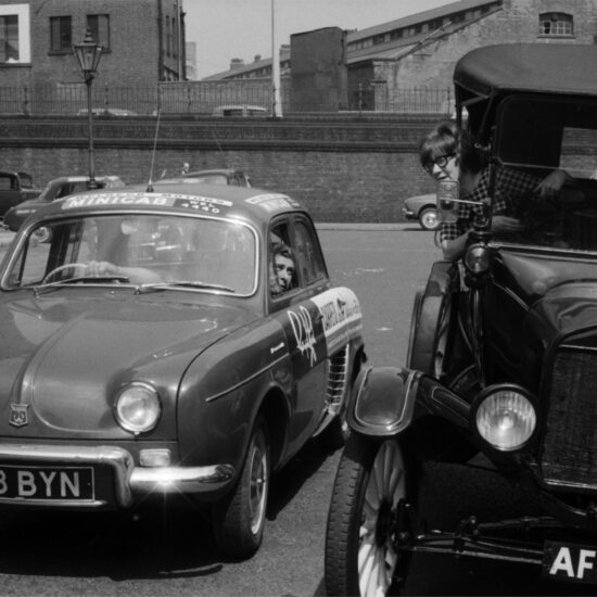 Two Welbeck Motors minicabs are parked in Balcombe Street, London, adjacent to a black vintage motorcar from the 1930’s. A male driver in one of the Welbeck minicabs appears to be chatting with the female driver of the vintage motorcar. Circa 1961